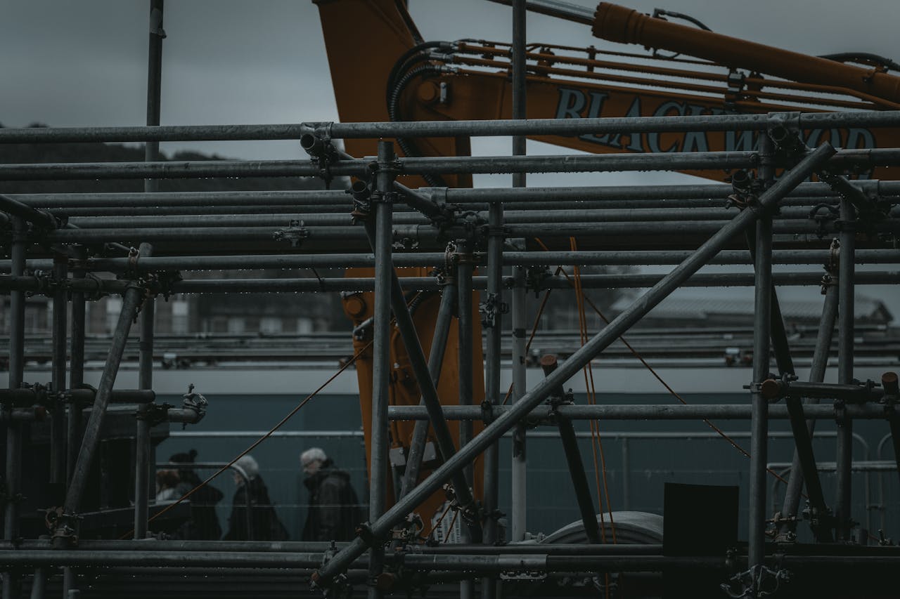 Scaffolding and machinery in an industrial setting with people in the background in Edinburgh, Scotland.