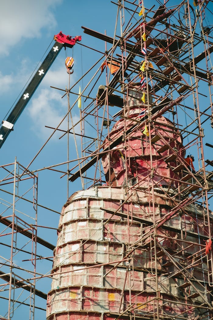 A temple dome under construction with scaffolding against a clear blue sky.