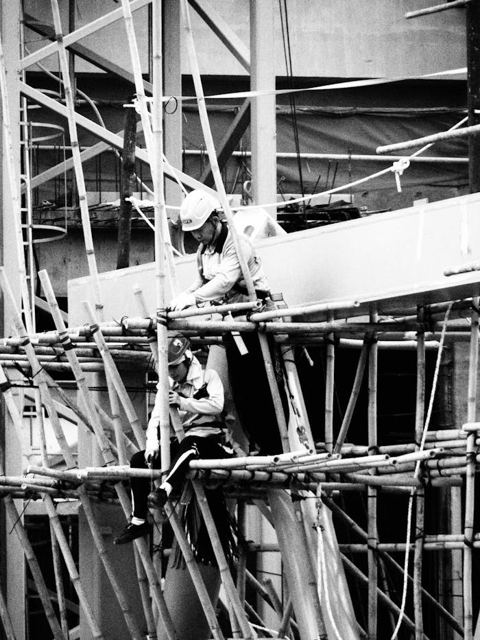 Black and white image of construction workers on a bamboo scaffold in Hong Kong.